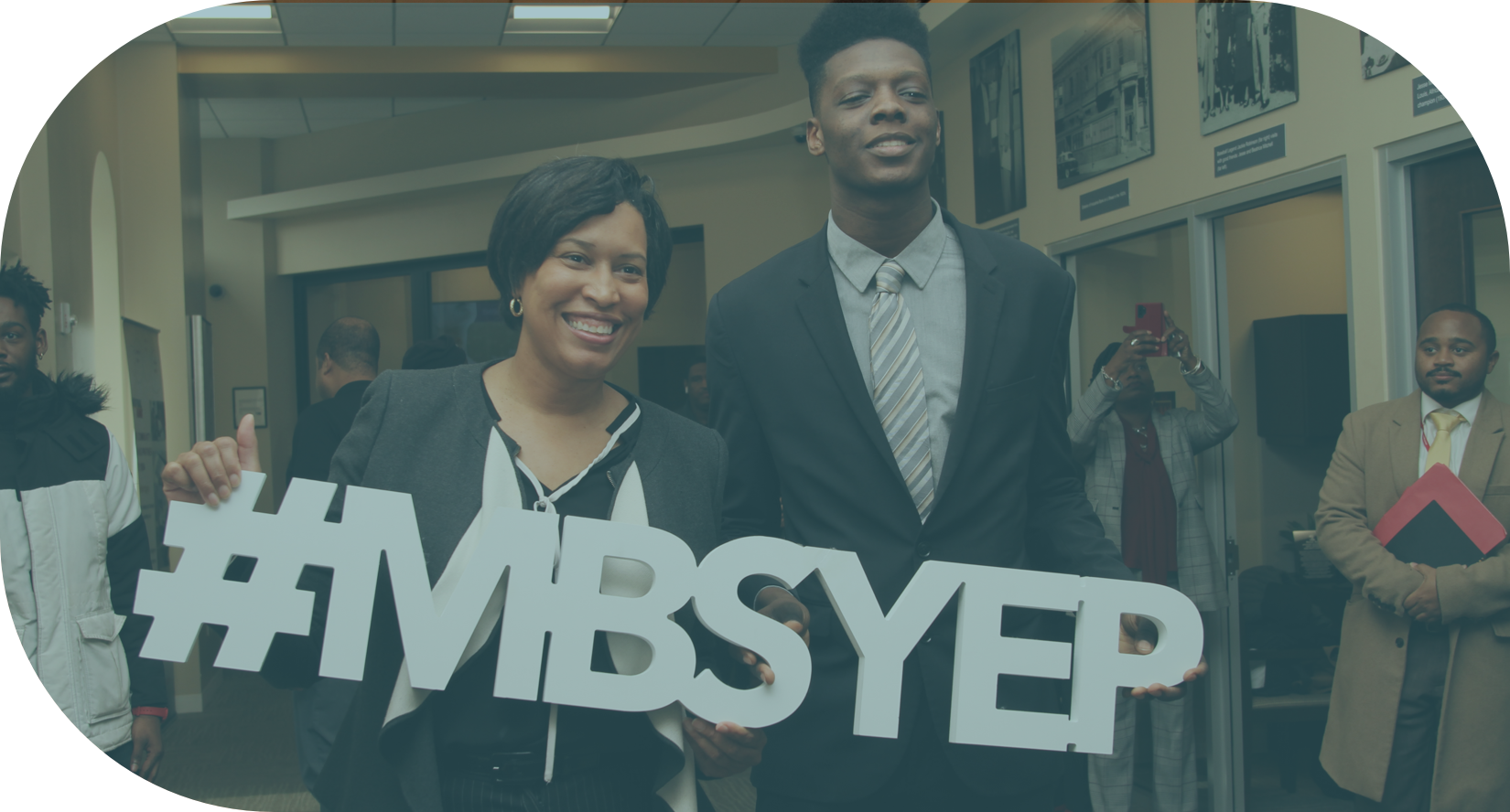 Image of Mayor Bowser and a young man holding up a sign that reads #MBSYEP